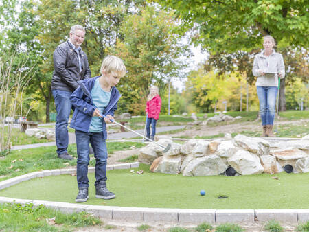Een gezin golft op de midgetgolfbaan van vakantiepark Landal Hochwald