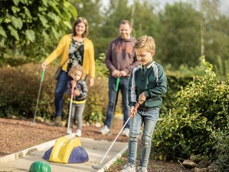 Gezin golft op de midgetgolfbaan van vakantiepark Landal Hunerwold State