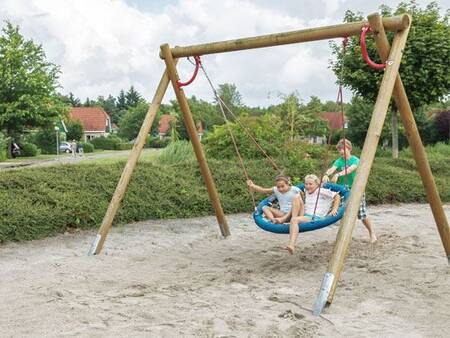 Kinderen op een schommel van een speeltuin op vakantiepark Landal Hunerwold State