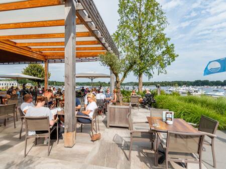 Mensen op het terras van Beachclub Leukermeer op vakantiepark Landal Marina Resort Well