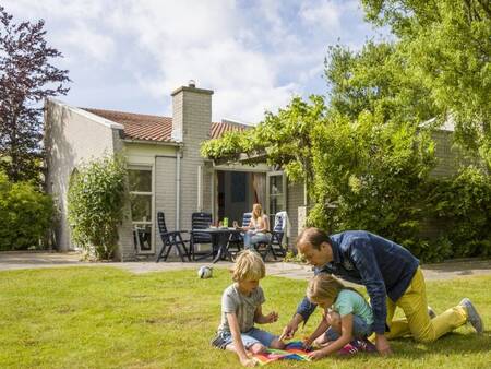 Gezin speelt in de tuin van een vakantiehuis op vakantiepark Landal Port Greve