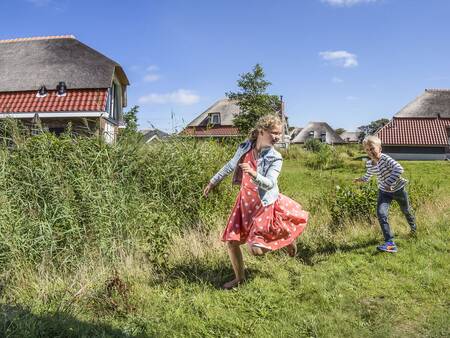 Kinderen spelen op het gras bij vakantiehuizen op vakantiepark Landal Sluftervallei