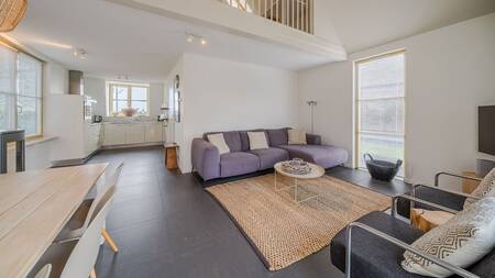 Woonkamer met banken eettafel en open keuken van een vakantiehuis op Landal Vakantiepark Duynvallei
