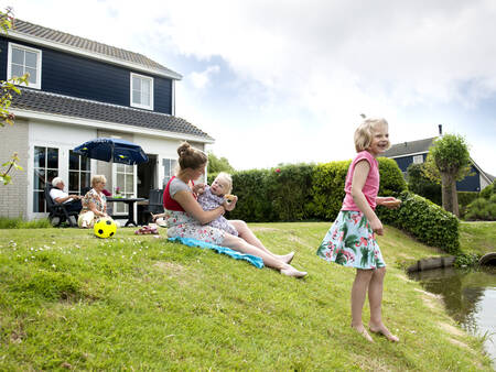 Gezin in de tuin van een villa aan het water op vakantiepark Landal Villapark Livingstone