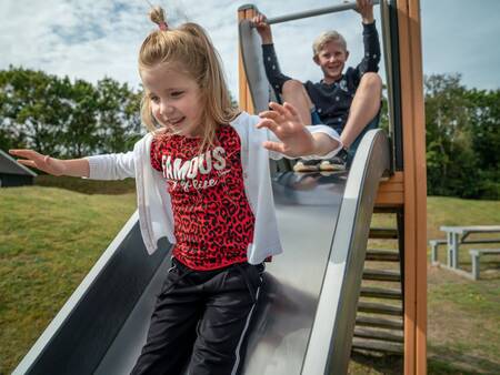 Kinderen glijden van een glijbaan in een speeltuin bij Landal Vitamaris