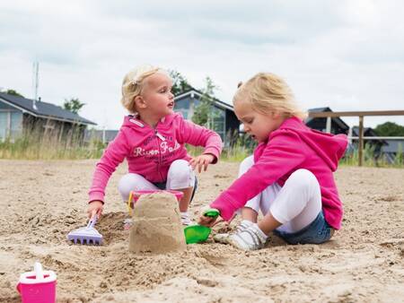 Kinderen spelen in het zand op het recreatiestrand van vakantiepark Landal Waterpark Sneekermeer