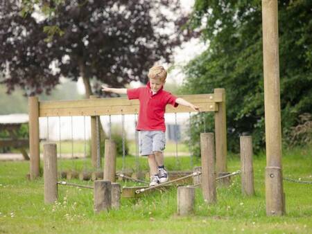 Jongetje balanceert op een speeltoestel in een speeltuin op Landal Waterpark Sneekermeer