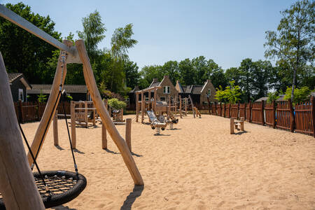 Buitenspeeltuin met houten speeltoestellen op vakantiepark Landgoed De IJsvogel