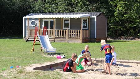 Een klein speeltuintje tussen chalets op een veld op vakantiepark Molecaten Bosbad Hoeven