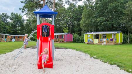 Kinderen spelen in een kleine speeltuin tussen chalets op vakantiepark Molecaten het Landschap