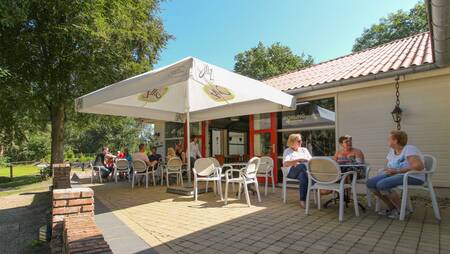 Mensen op het terras bij het restaurant en snackbar op vakantiepark Molecaten Park De Koerberg