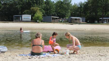 Gezin aan het spelen in het zand van het recreatiemeer op vakantiepark Molecaten Park Kuierpad