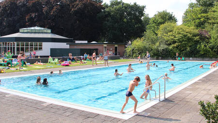 Mensen aan het zwemmen in het buitenbad van vakantiepark Molecaten Park Landgoed Ginkelduin