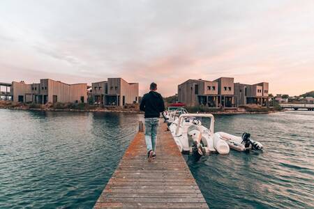 Man loopt langs boten aan een aanlegsteiger op vakantiepark Oasisparcs Oasis Punt West