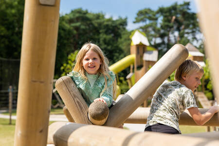 Kinderen op een houten speeltoestel in de speeltuin op vakantiepark RCN de Jagerstee
