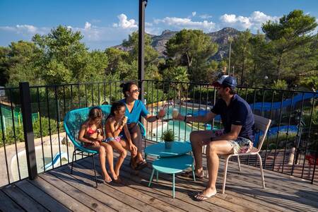 Gezin zit op het terras bij het buitenbad van vakantiepark RCN Domaine de la Noguière