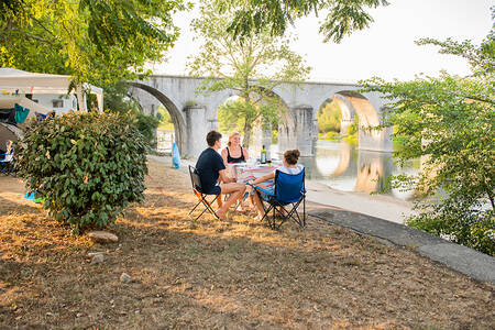 Mensen zitten naast de rivier de Ardèche op vakantiepark RCN La Bastide en Ardèche