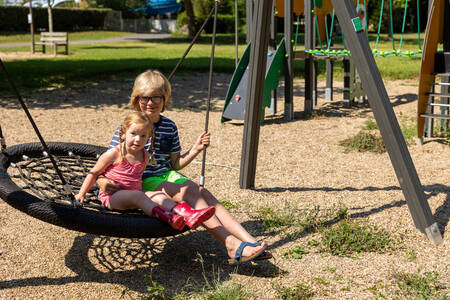 Kinderen op de schommel in een speeltuin op vakantiepark RCN Le Moulin de la Pique