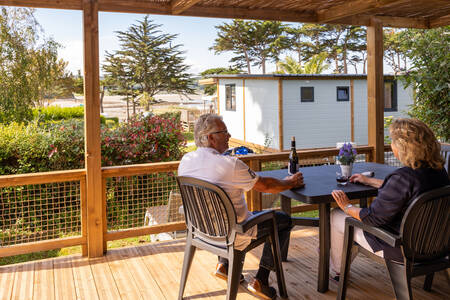 Stel zit op de veranda van een mobil home op vakantiepark RCN Port l’Epine