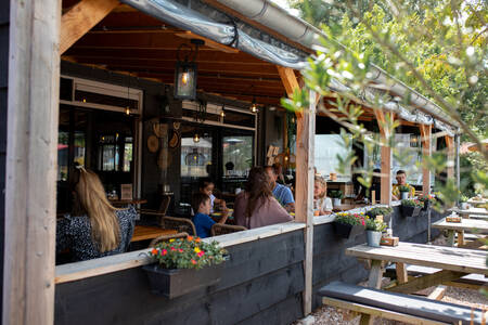 Mensen aan het eten op het overdekte terras bij het restaurant op vakantiepark RCN Toppershoedje