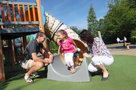 Kinderen glijden van de glijbaan in een speeltuin op vakantiepark Roompot Bospark de Schaapskooi