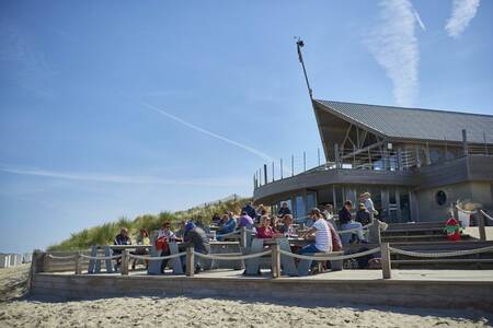 Mensen op het terras van een strandtent vlakbij vakantiepark Roompot Breeduyn Village