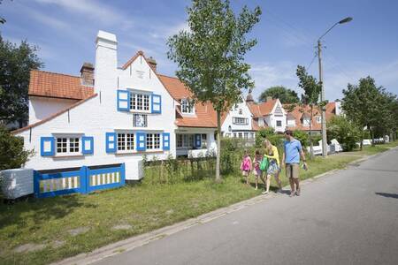 Een gezin wandelt langs vakantiehuizen op vakantiepark Roompot Breeduyn Village