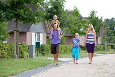 Gezin wandelt voor vakantiehuizen op vakantiepark Roompot Buitenplaats De Hildenberg