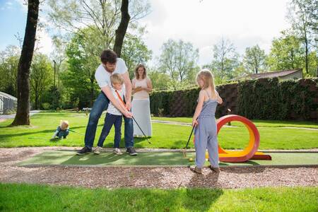 Gezin aan het golfen op de minigolf van vakantiepark Roompot Bungalowpark Hoenderloo