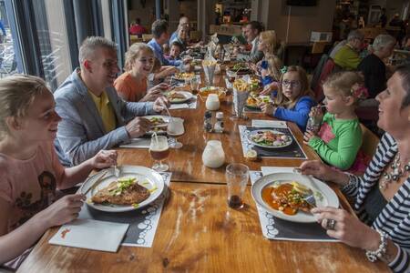 Familie dineert in het restaurant op vakantiepark Roompot De Katjeskelder