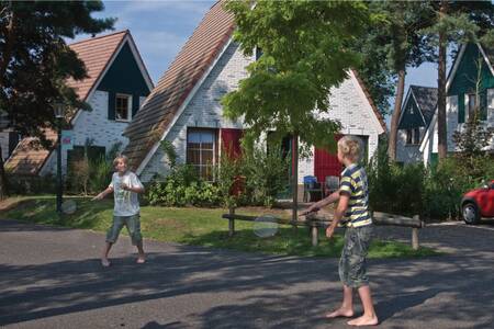 2 kinderen badmintonnen tussen de vakantiehuizen op vakantiepark Roompot De Katjeskelder