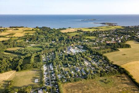 Luchtfoto van chalets op vakantiepark Roompot Deux Fontaines met de zee aan de horizon