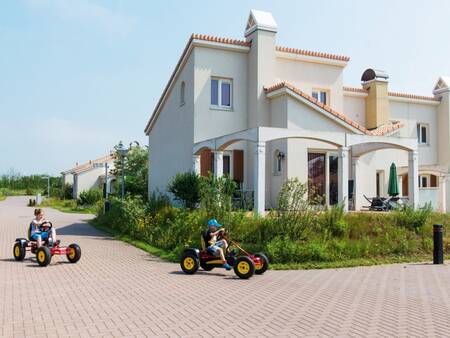 Kinderen op skelters en een huis met mediterrane uitstraling op Roompot Duinresort Dunimar