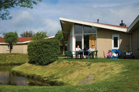 Gezin op het terras van een vakantiehuis aan het water op vakantiepark Roompot Hof Domburg