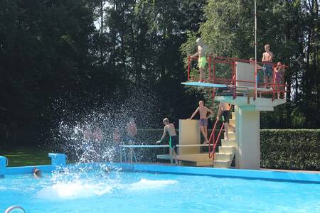 Mensen op de duikplank in het buitenbad van vakantiepark Roompot Hunzepark