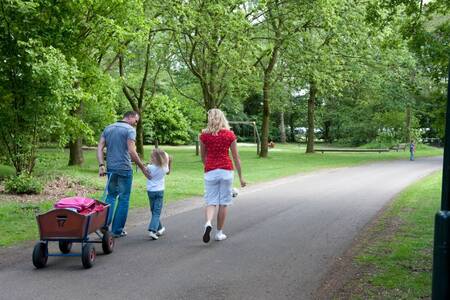 Gezin met een bolderwagen wandelt over vakantiepark Roompot Klein Vink