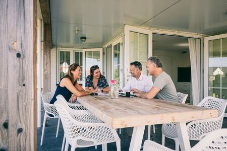 Mensen aan een tafel bij een vakantiehuis op vakantiepark Roompot Noordzee Résidence Cadzand-Bad