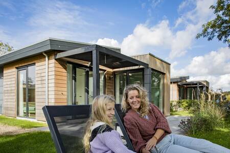 Mensen op ligstoelen in de tuin van een vakantiehuis op vakantiepark Roompot Park Wijdenes