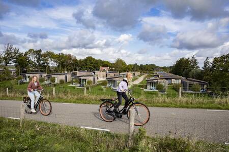 Mensen fietsen op de dijk tussen vakantiepark Roompot Park Wijdenes en het Markermeer