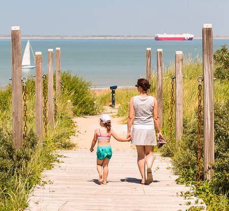 Mensen wandelen naar het strand aan het Grevelingenmeer vlakbij Roompot Park Zeedijk