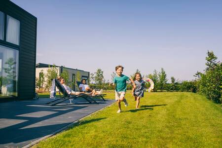 Mensen in de tuin van een vakantiehuis op vakantiepark Roompot Park Zeedijk