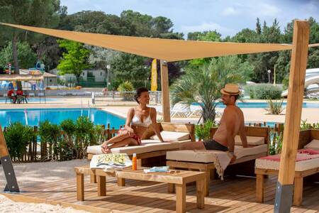 Een stelletje op ligbedden bij het buitenbad van vakantiepark Roompot Plein Air des Chênes