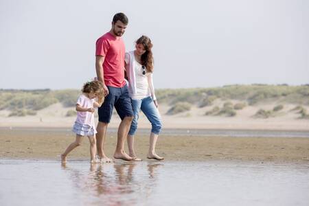 Mensen wandelen over het strand nabij Ouddorp en vakantiepark Roompot Strandpark Duynhille