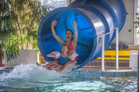 Moeder en dochter op de glijbaan in het binnenbad van Roompot Vakantiepark Aquadelta