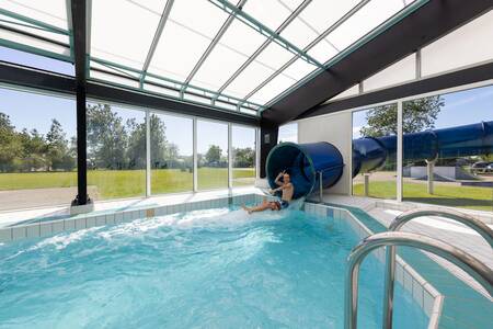 Jongen op de grote glijbaan in het binnenbad van Roompot Vakantiepark Callassande