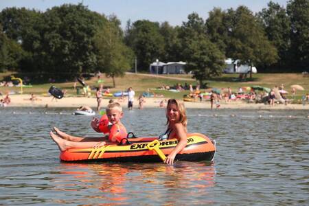 Vrouw met kindje in een rubberboot op het recreatiemeer van Roompot Vakantiepark Hunzedal