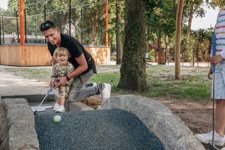 Mensen golfen op de midgetgolfbaan van Roompot Vakantiepark Kijkduin