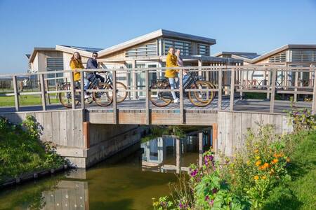 Mensen op een brug en vakantiehuizen op vakantiepark Roompot Water Village