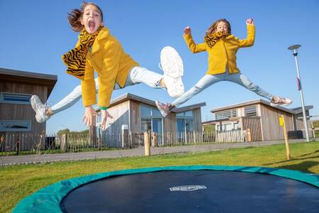 Kinderen springen op een trampoline bij een vakantiehuis op vakantiepark Roompot Water Village
