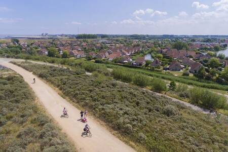 Mensen fietsen door de duinen naast vakantiepark Roompot Zeebad